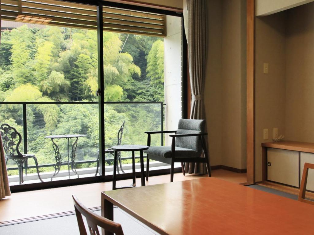 Cette chambre dispose d'une grande fenêtre, d'une table et de chaises. dans l'établissement Saga Fuga, à Saga