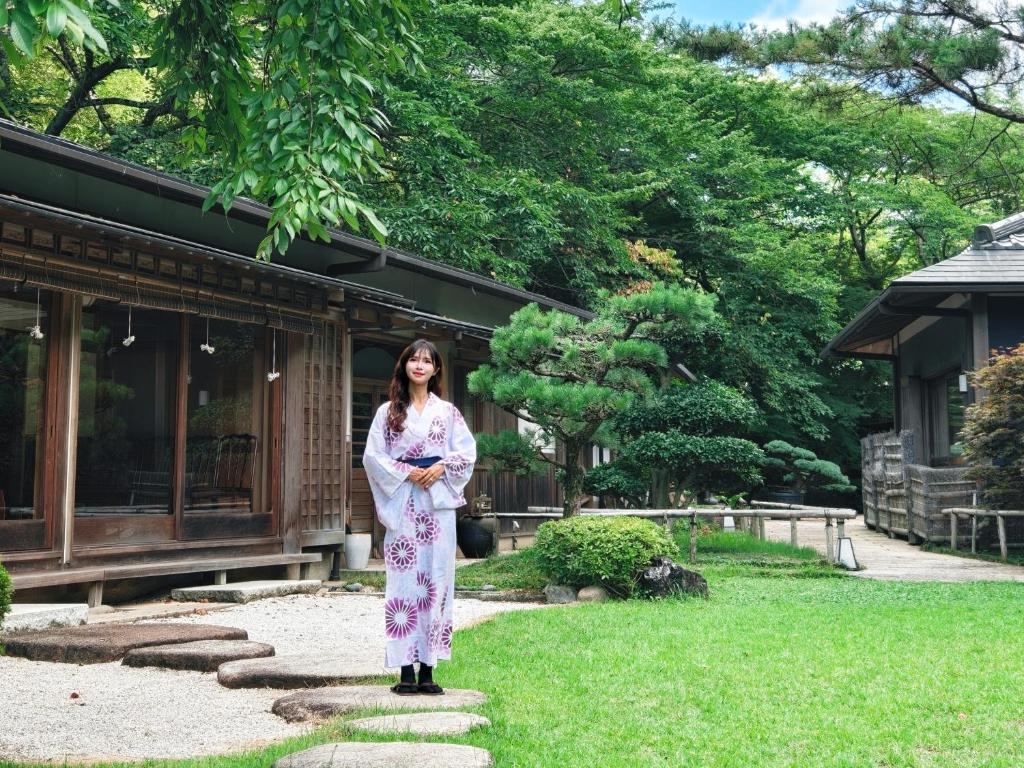 une femme en robe debout dans un jardin dans l'établissement Oukai Villa Izumi, à Izumi