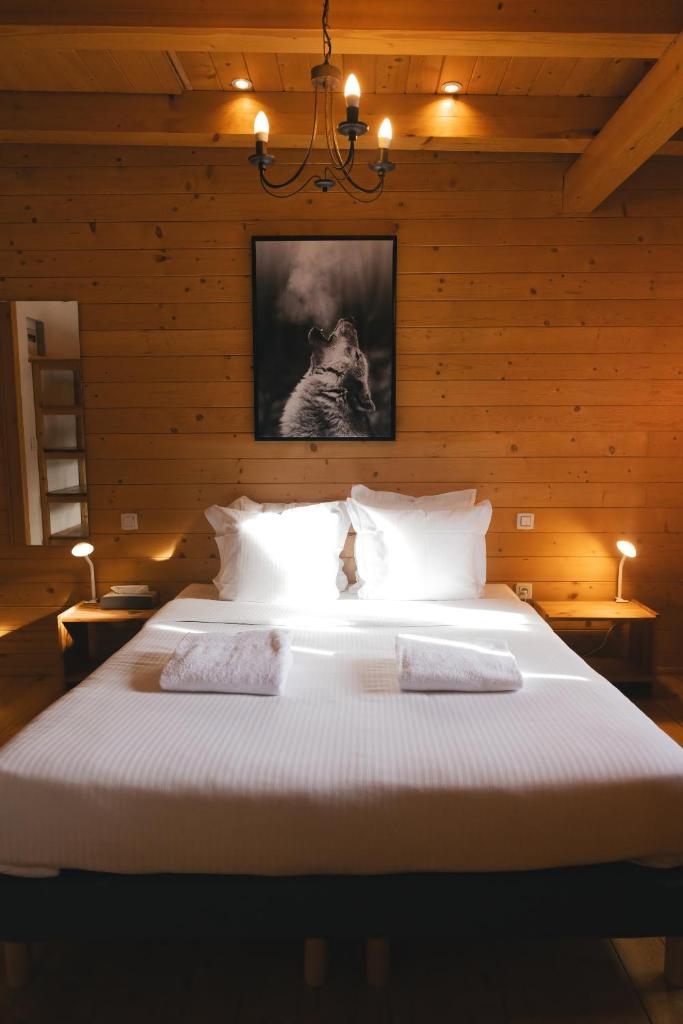 - une chambre avec un grand lit blanc et des murs en bois dans l'établissement Le Loup Blanc, à Pra-Loup