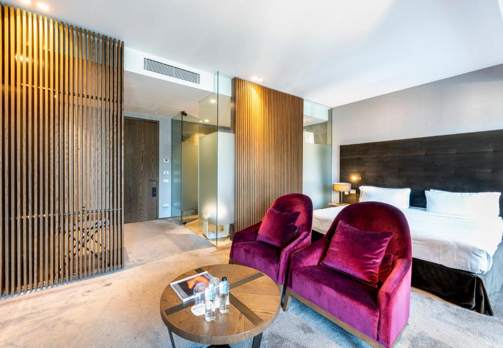 une chambre d'hôtel avec un lit, une chaise violette et une table dans l'établissement Grand Hotel Campione, à Campione dʼItalia