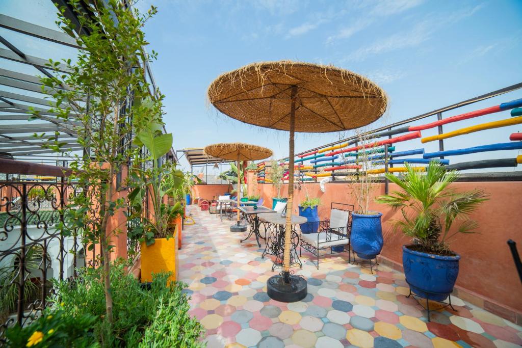 un patio avec des tables et des chaises, des parasols et des plantes dans l'établissement Riad Arabic House & Spa, à Marrakech