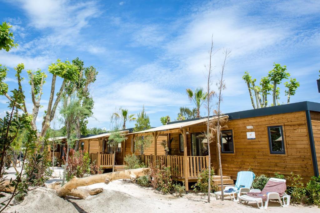 une maison en bois avec 2 chaises et une terrasse couverte dans l'établissement Vic's Land Holidays, à Grimaud