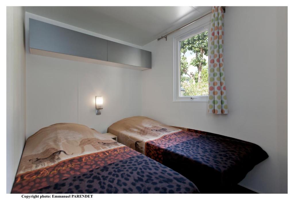 une chambre avec deux lits et une fenêtre dans l'établissement Vic's Land Holidays, à Grimaud