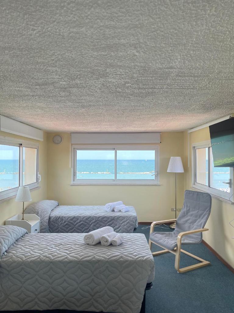 une chambre d'hôtel avec deux lits et une chaise dans l'établissement Hotel Pironi, à San Mauro a Mare