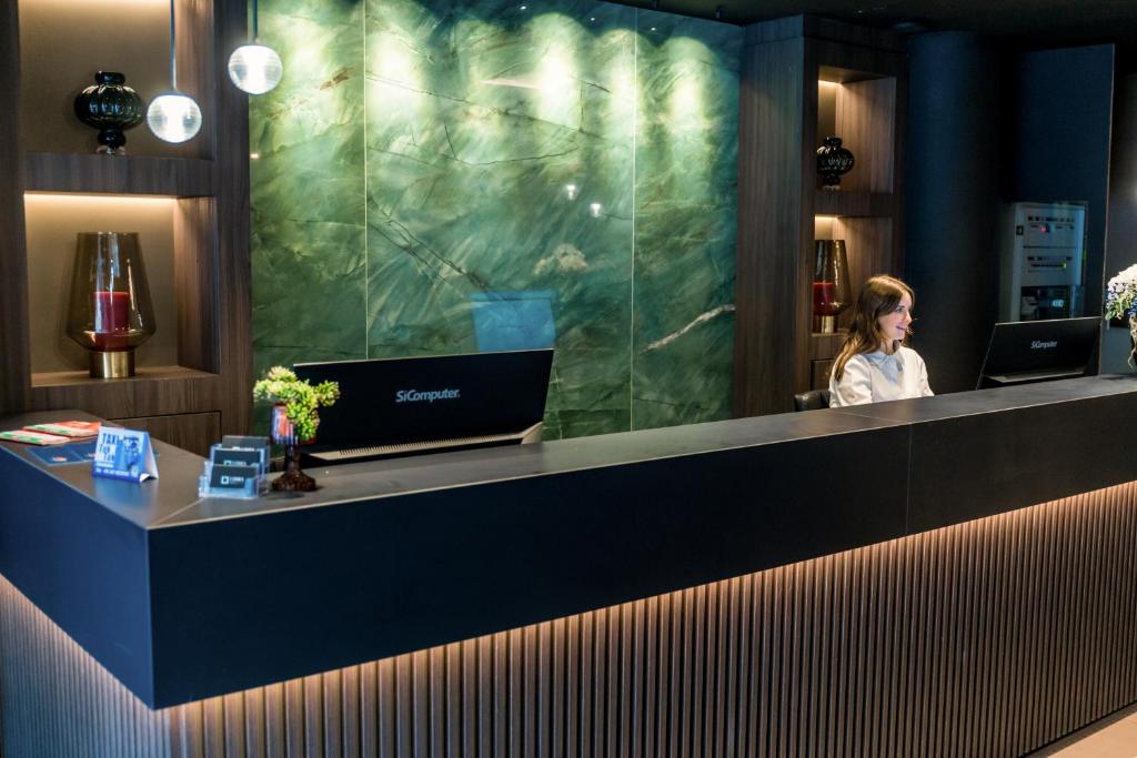 une femme assise au comptoir dans un hall dans l'établissement Lumia Hotel, à Termoli