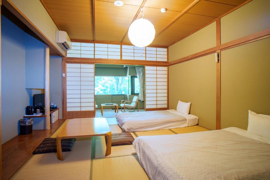 une chambre avec deux lits et une table dans l'établissement Kozuka Hisanoha, à Hakone