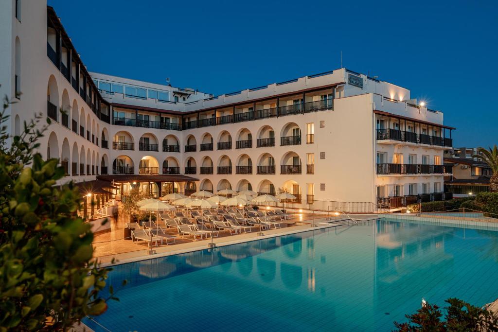 un hôtel avec une piscine devant un bâtiment dans l'établissement Hotel Calabona, à Alghero