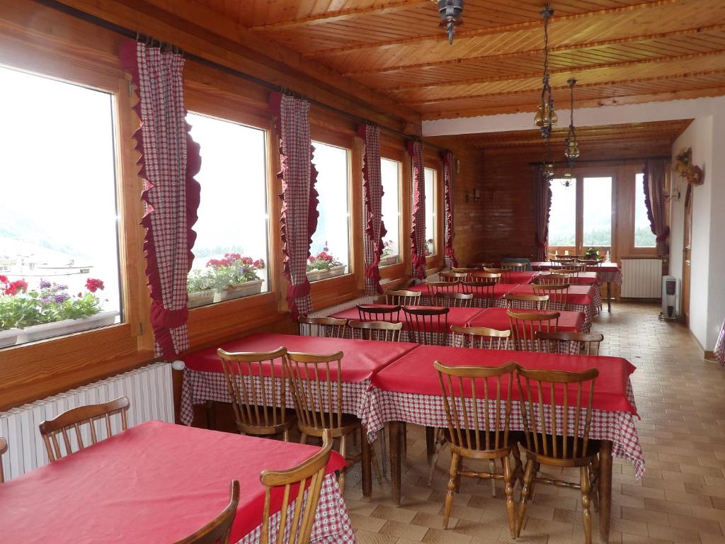 un restaurant avec des tables rouges, des chaises et des fenêtres dans l'établissement Hôtel les skieurs, à Bellevaux