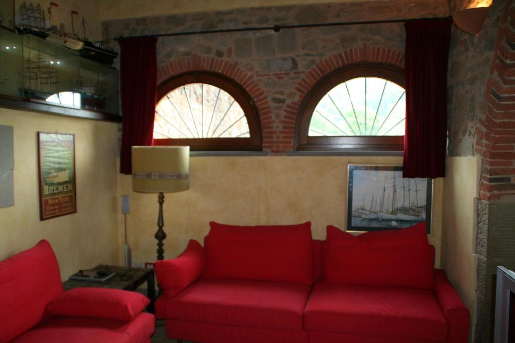 - un salon avec deux canapés rouges et deux fenêtres dans l'établissement Podere Gianpaolo, à Pescia