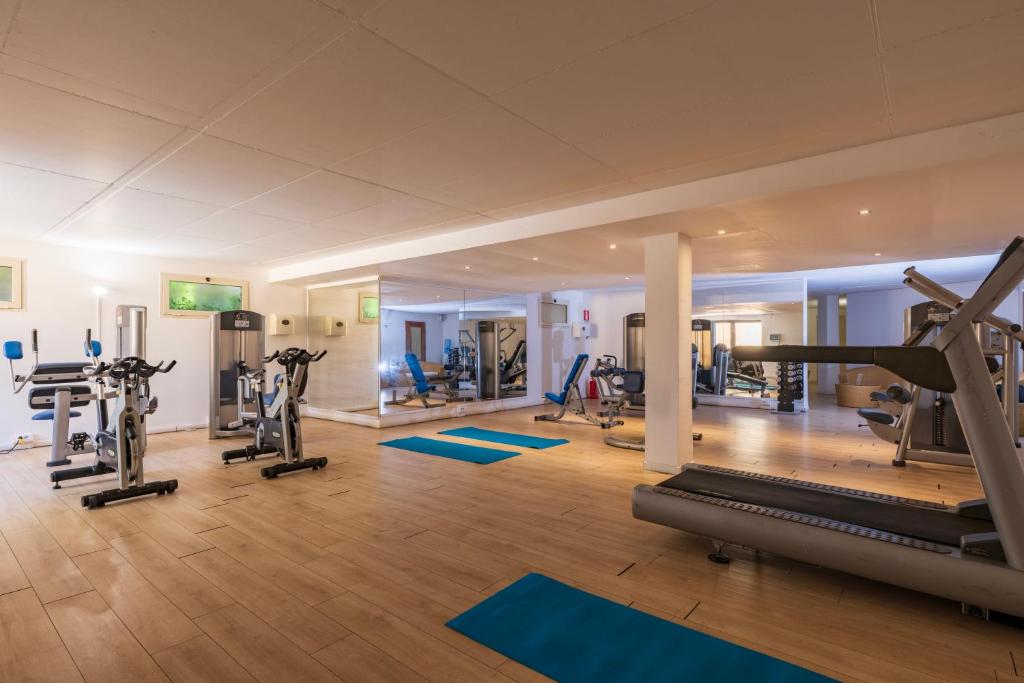 une salle de sport avec des tapis roulants et des appareils d'exercice dans un bâtiment dans l'établissement Janna e Sole Resort, à Budoni