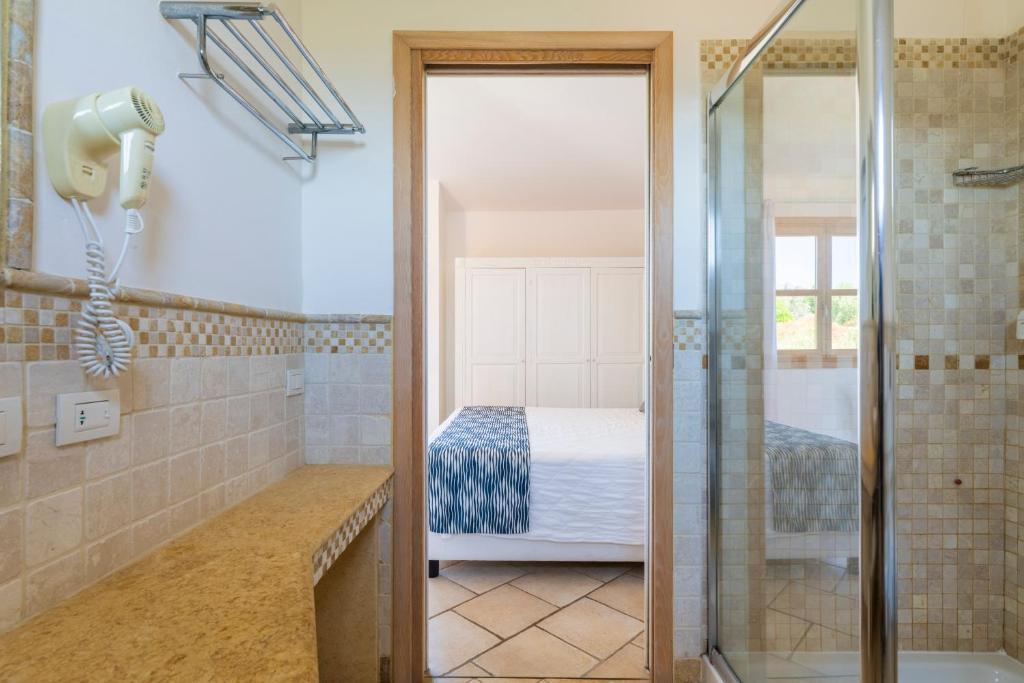 une salle de bain avec douche et un lit dans l'établissement Janna e Sole Resort, à Budoni