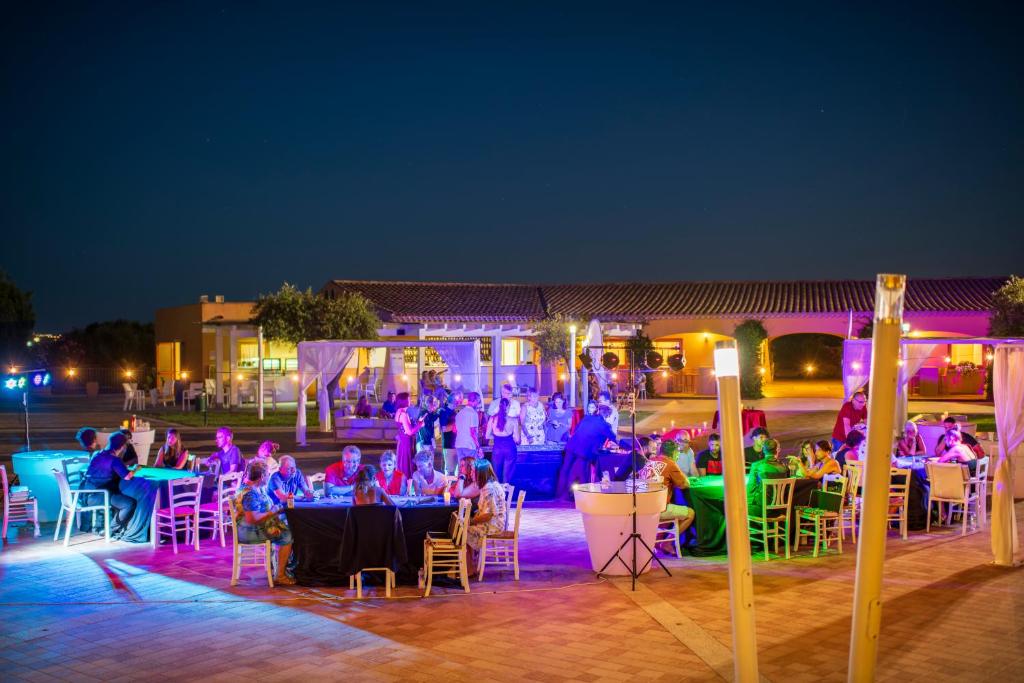 un groupe de personnes assises à des tables la nuit dans l'établissement Janna e Sole Resort, à Budoni 272 autres photos