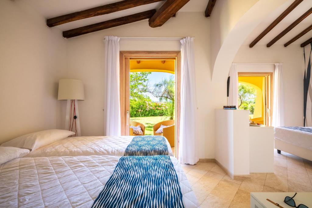 une chambre avec un lit et une grande fenêtre dans l'établissement Janna e Sole Resort, à Budoni
