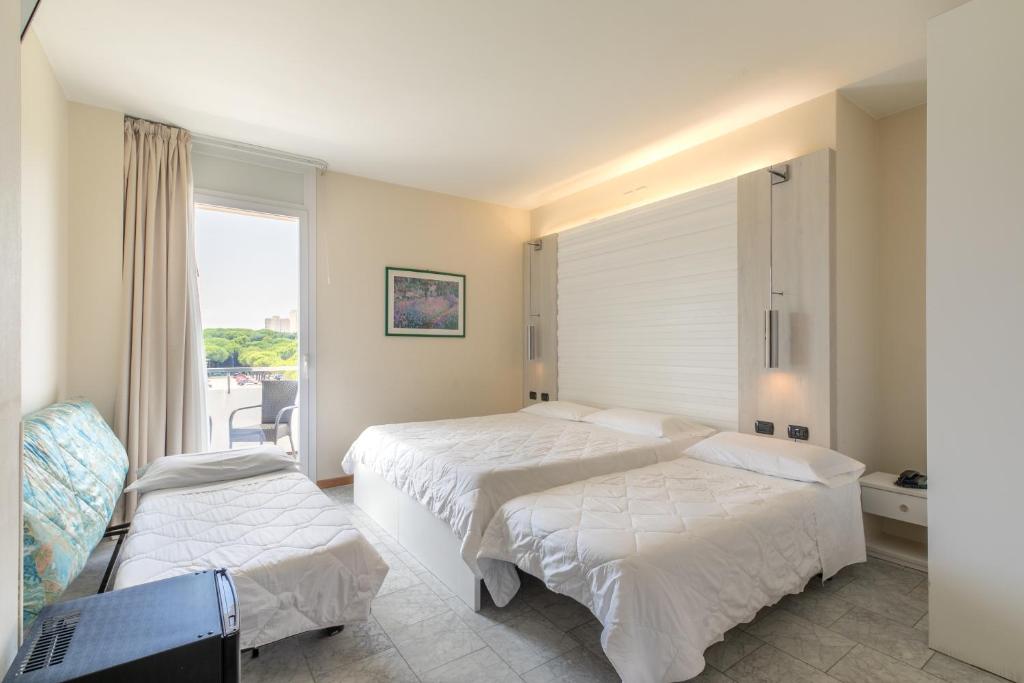 une chambre avec deux lits et une fenêtre dans l'établissement Hotel Consuelo, à Lignano Sabbiadoro