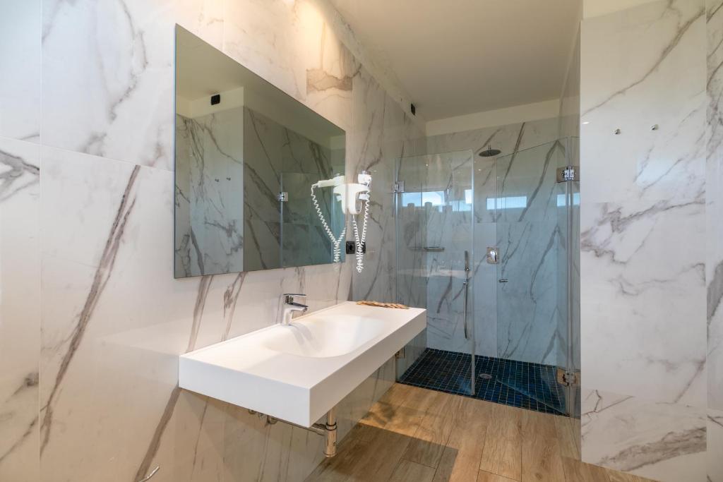 une salle de bain blanche avec lavabo et douche dans l'établissement Hotel Consuelo, à Lignano Sabbiadoro