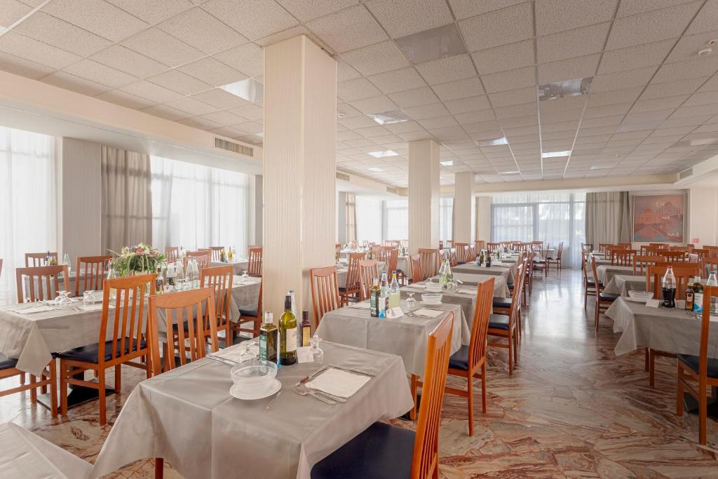 une salle à manger avec des tables et des chaises avec des nappes blanches dans l'établissement Hotel Dell'Angelo, à Rimini