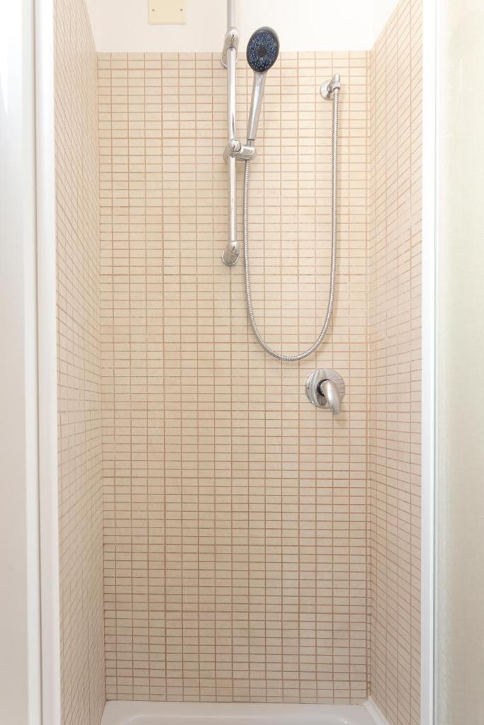 La salle de bains est pourvue d'une douche et d'un mur carrelé. dans l'établissement Hotel Dell'Angelo, à Rimini