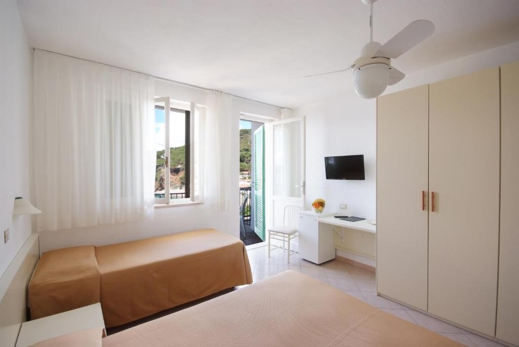 une chambre avec un lit, un bureau et une fenêtre dans l'établissement Hotel Dino, à Capoliveri