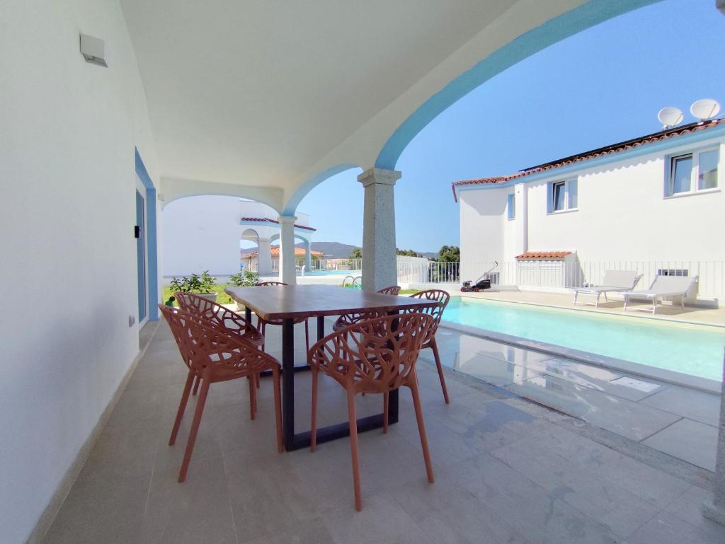 un patio avec une table et des chaises à côté d'une piscine dans l'établissement Villa il borgo con piscina, à Budoni 6 autres photos
