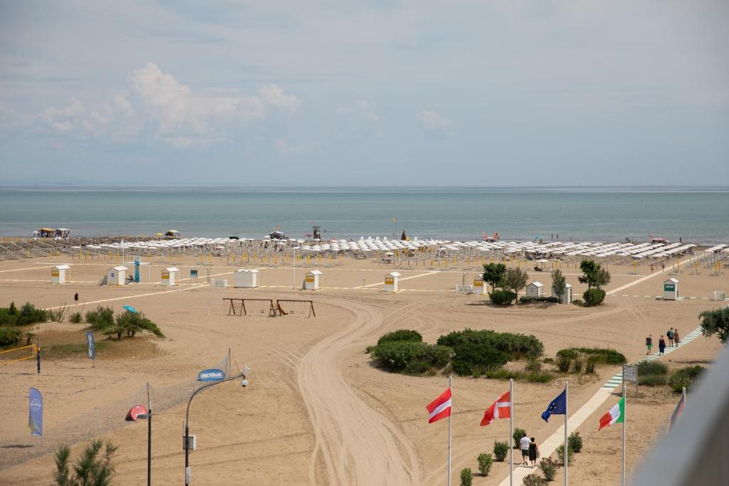 une plage de sable avec des parasols blancs et l'océan dans l'établissement Hotel Benvenuto, à Caorle