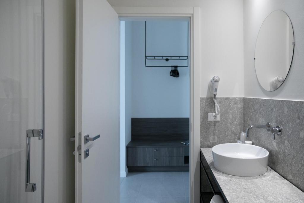 une salle de bain avec un lavabo blanc et un miroir dans l'établissement Hotel Benvenuto, à Caorle