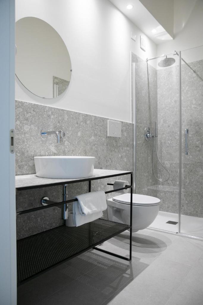 une salle de bain avec un lavabo, des toilettes et une douche dans l'établissement Hotel Benvenuto, à Caorle