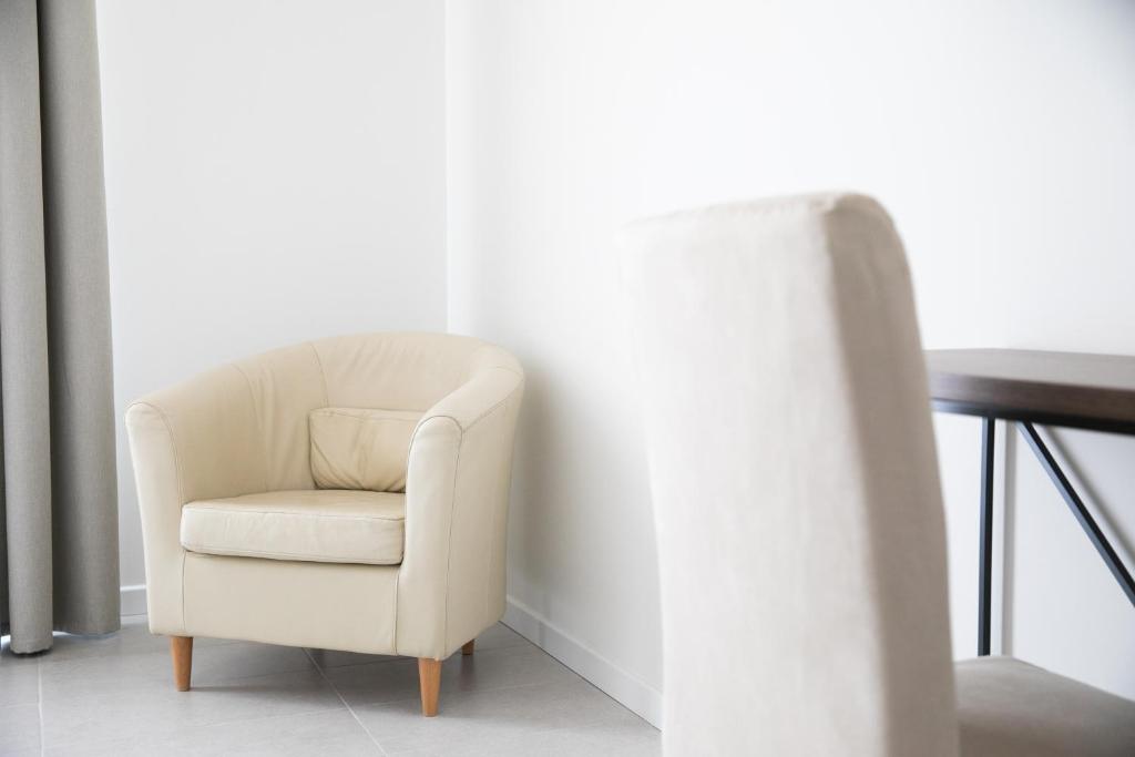 une chaise blanche assise dans une pièce à côté d'une table dans l'établissement Hotel Benvenuto, à Caorle