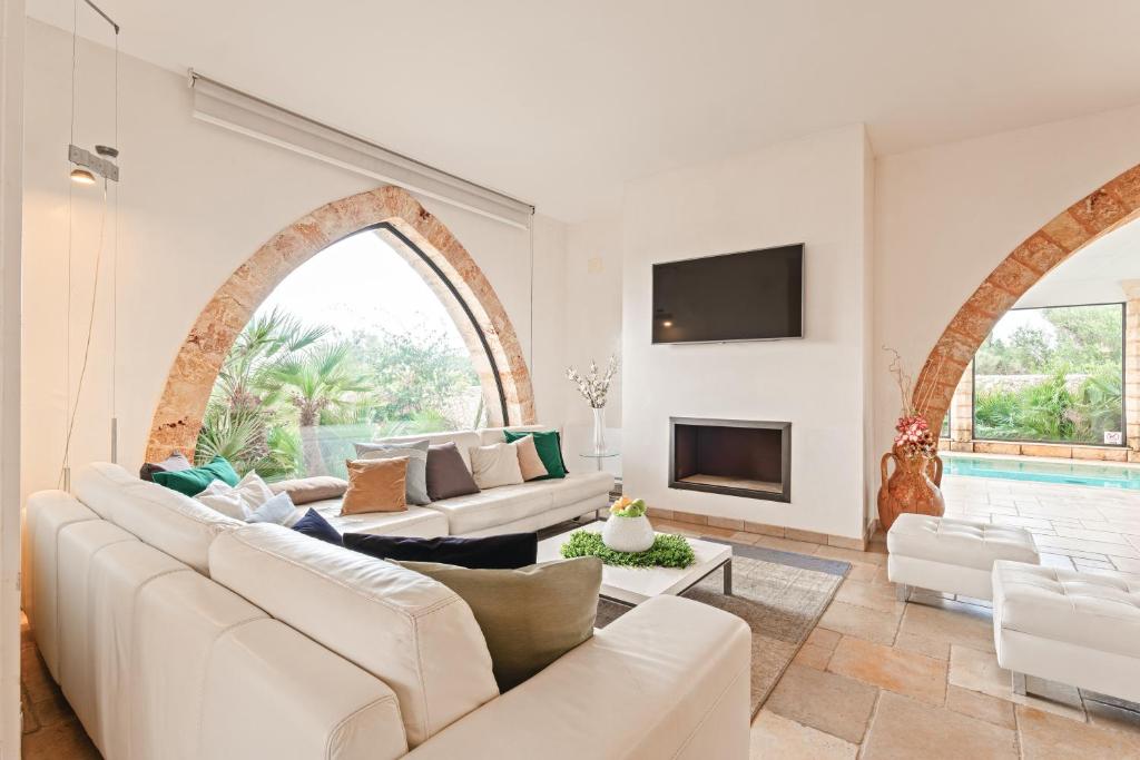 Elle comprend un salon doté d'un mobilier blanc et d'une fenêtre cintrée. dans l'établissement Villa Manco 12, Emma Villas, à Gagliano del Capo