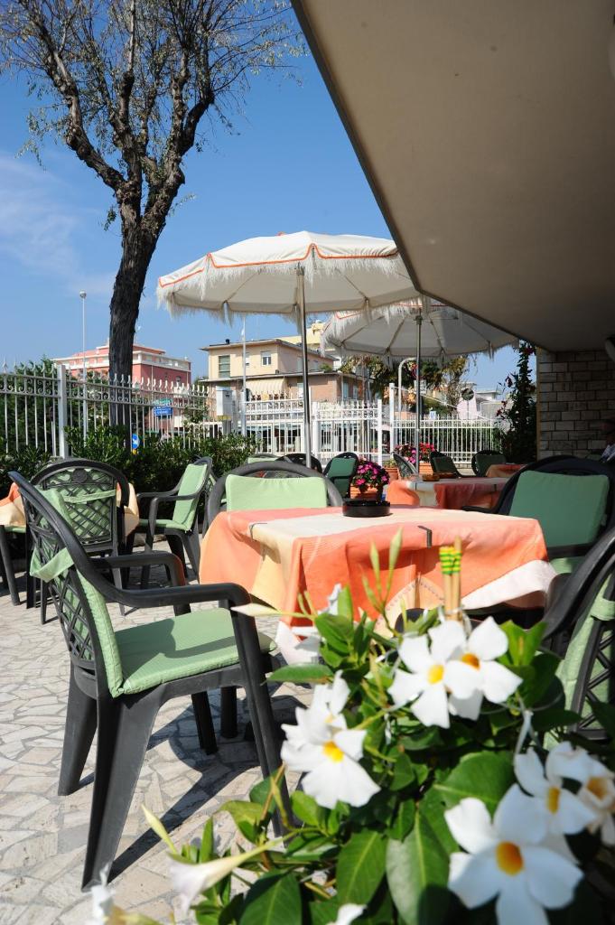 d'une terrasse avec des tables et des chaises et des fleurs blanches. dans l'établissement Hotel Biagini, à Rimini