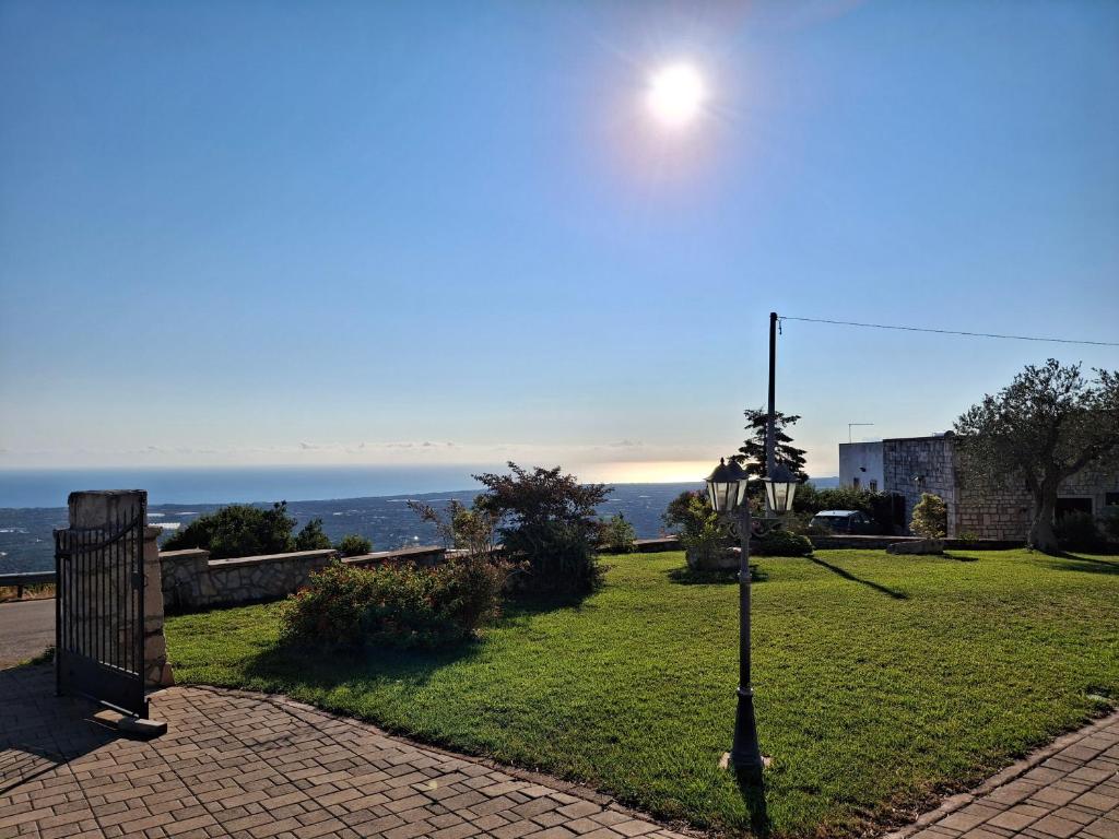 un lampadaire sur un champ d'herbe avec l'océan en arrière-plan dans l'établissement Panoramic trulli with swimming pool in Monopoli, à Monopoli