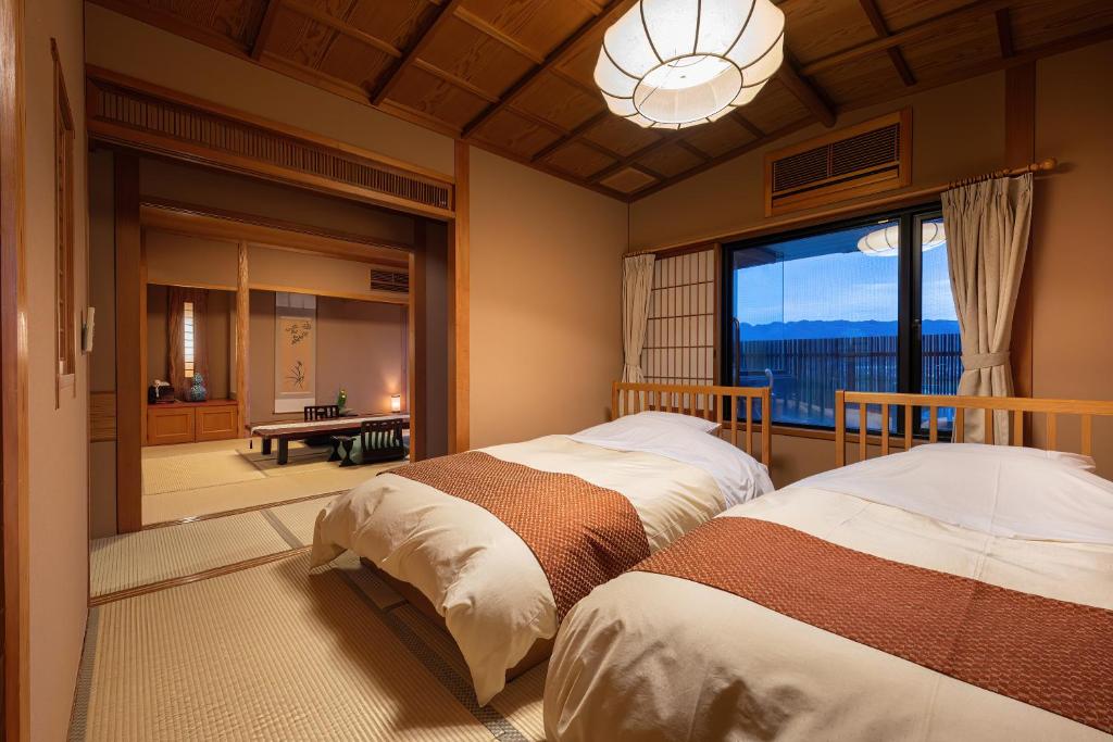 deux lits dans une chambre avec une grande fenêtre dans l'établissement Roppokan, à Asakura