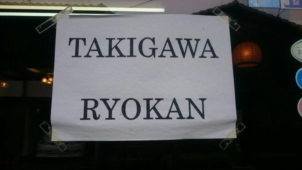 un panneau indiquant un ryokan suspendu à un poteau dans l'établissement Takigawa Ryokan, à Kyoto