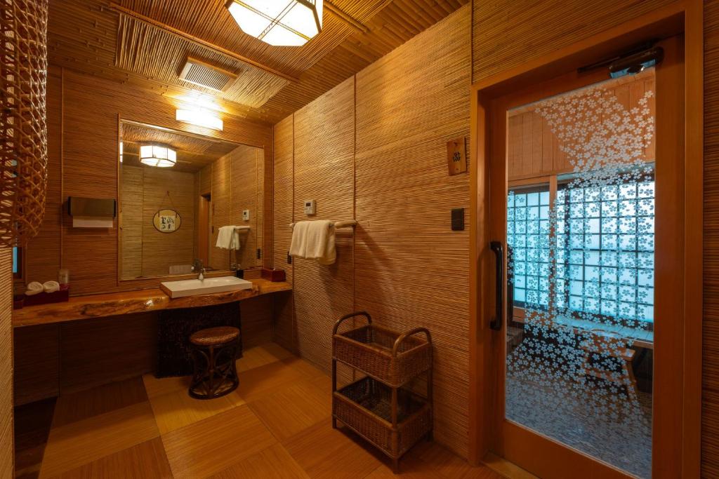 une salle de bain avec une douche, un lavabo et un miroir dans l'établissement Wanosato, à Takayama