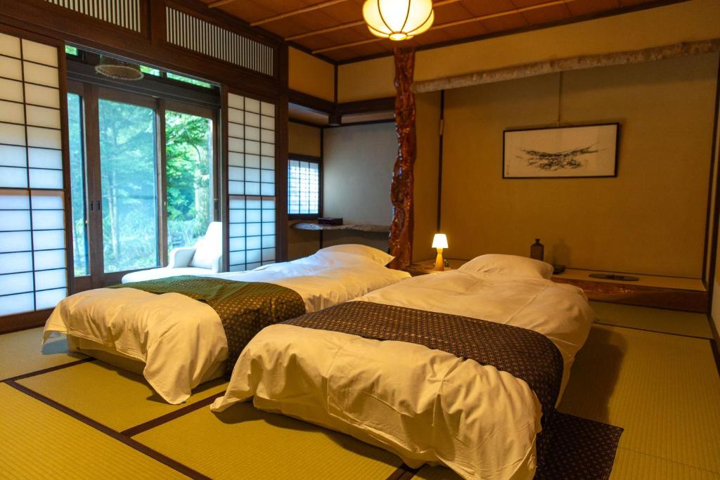 une chambre avec trois lits dans une pièce dans l'établissement Wanosato, à Takayama