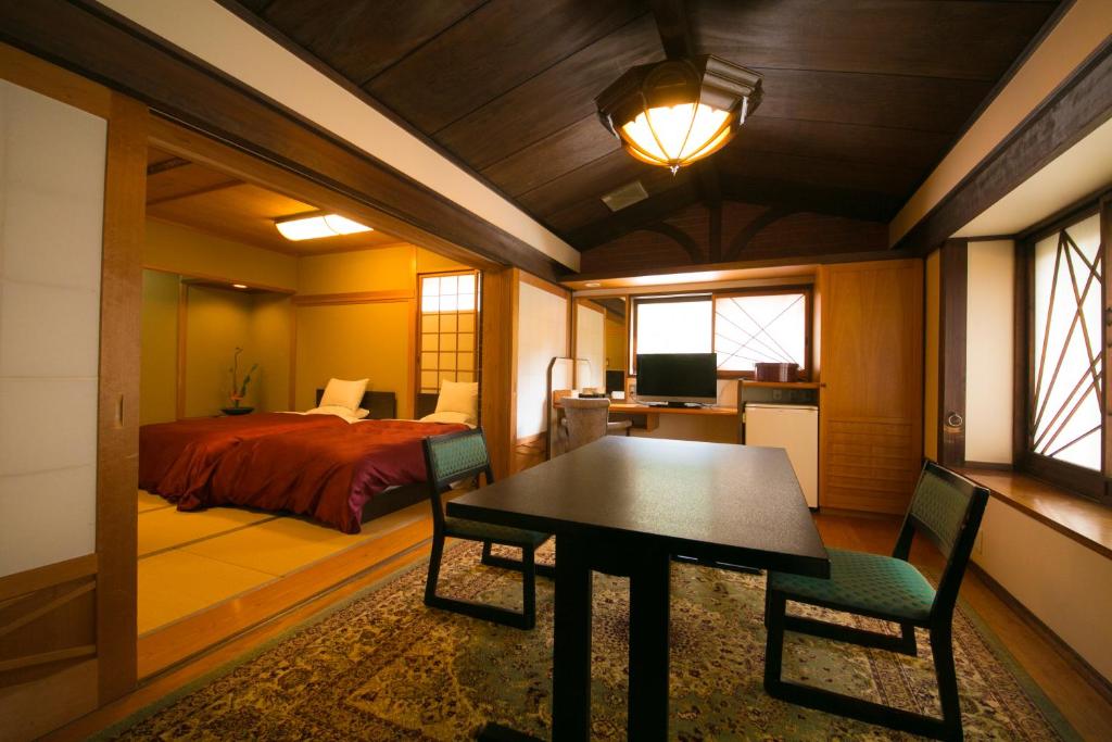 une chambre avec un lit, une table et des chaises dans l'établissement Ryotei Tanokura, à Yufu
