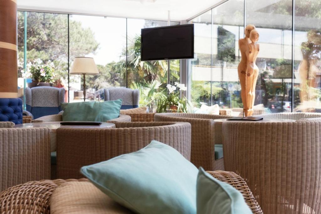 une chambre avec des chaises en osier et une statue d'une femme dans l'établissement Hotel Arizona, à Lignano Sabbiadoro