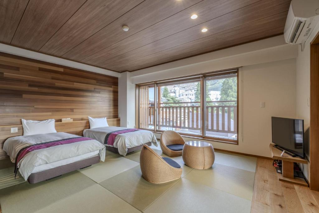 une chambre avec deux lits et une télévision à écran plat dans l'établissement Kawaichiya Ryokan, à Nozawa Onsen