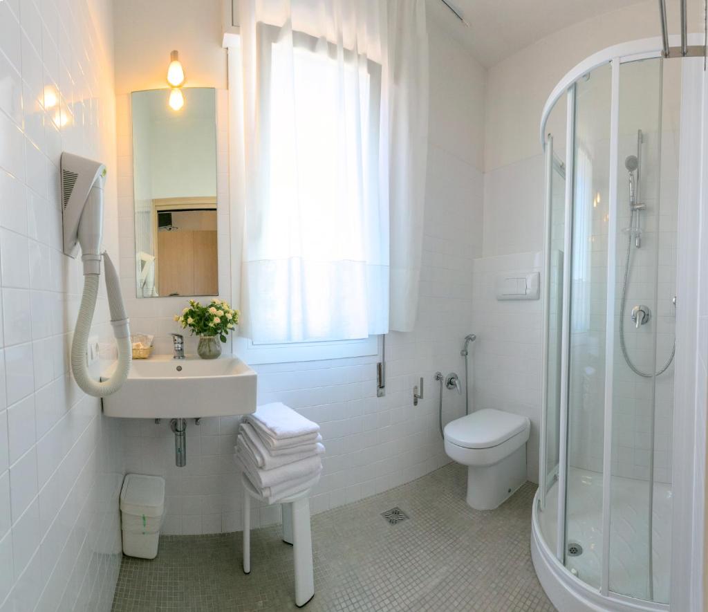 une salle de bain avec un lavabo, une douche et des toilettes dans l'établissement Hotel Colonna, à Lido di Jesolo