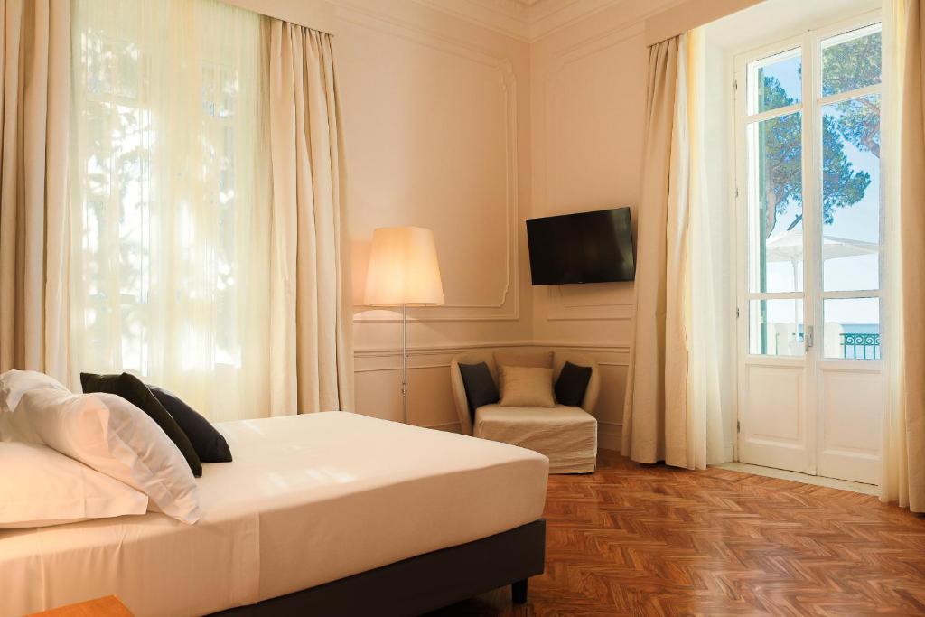 une chambre avec un lit, une fenêtre et une chaise dans l'établissement Villa Maria Teresa Boutique Hotel, à Formia