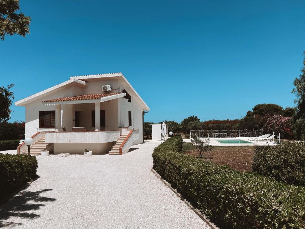 une maison blanche avec une allée et une piscine dans l'établissement Villa Stefano - avec piscine privée à Trapani, à Casa Luppini