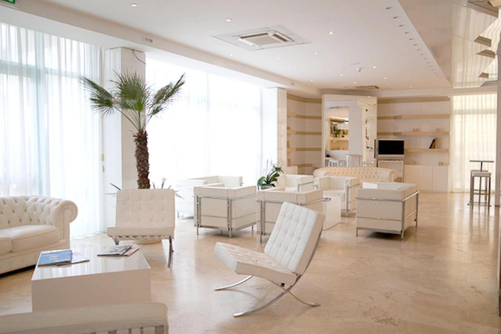 un salon avec des meubles blancs et un palmier dans l'établissement Hotel Excelsior, à Vasto