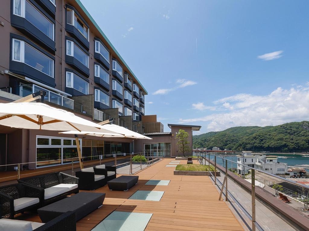 un hôtel avec une terrasse avec bancs et parasols dans l'établissement Sun Urashima Yuki no Sato, à Toba
