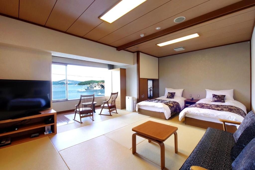 une chambre d'hôtel avec deux lits et une télévision à écran plat dans l'établissement Sun Urashima Yuki no Sato, à Toba