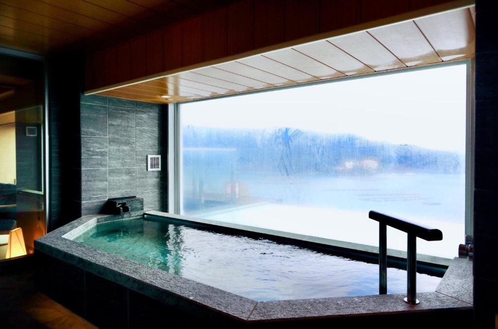 une grande piscine dans une pièce avec une grande fenêtre dans l'établissement Sun Urashima Yuki no Sato, à Toba