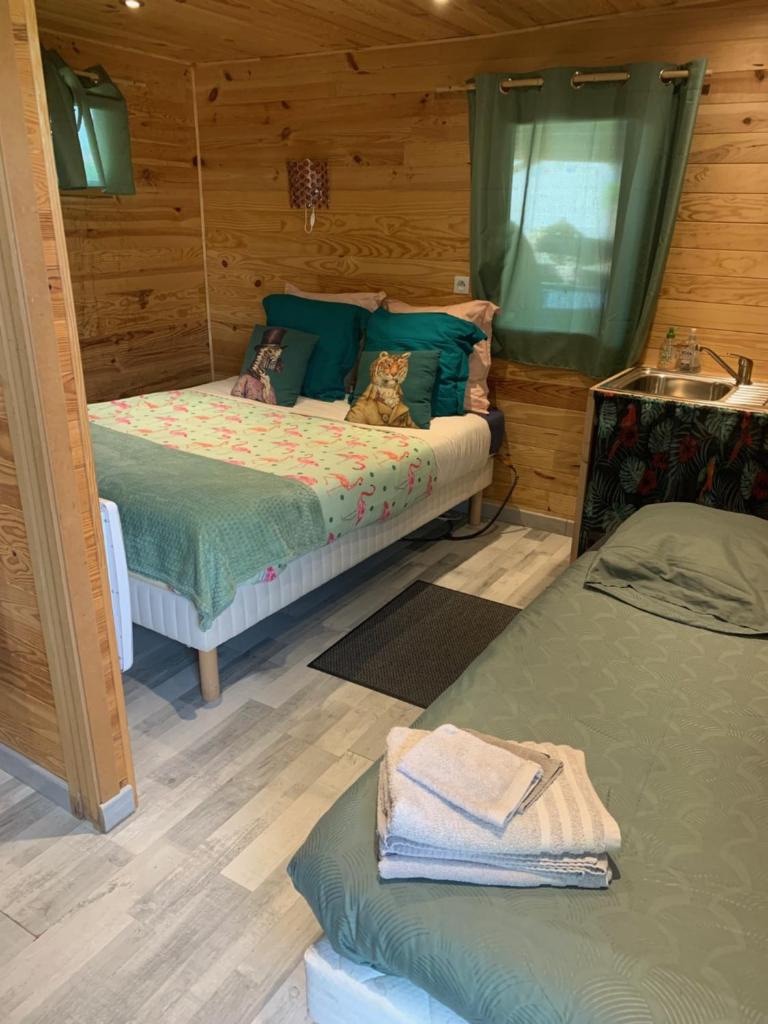 deux lits dans une chambre aux murs en bois dans l'établissement cabane bambou, à Huriel 26 autres photos