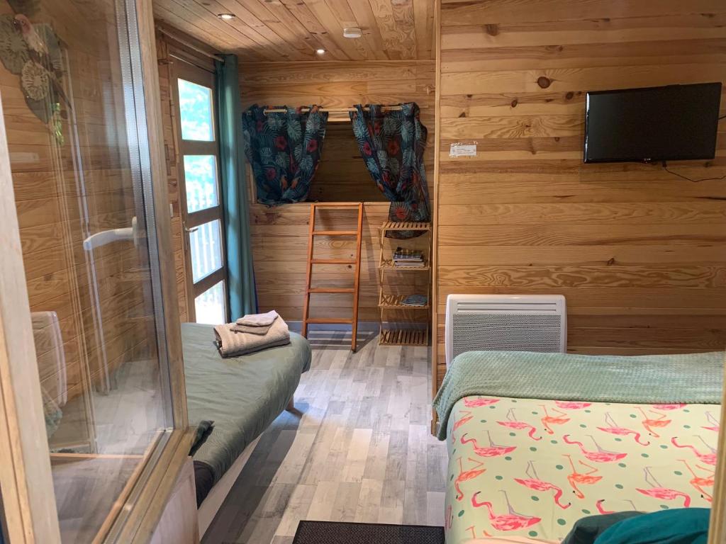 une petite chambre avec deux lits et une télévision dans l'établissement cabane bambou, à Huriel