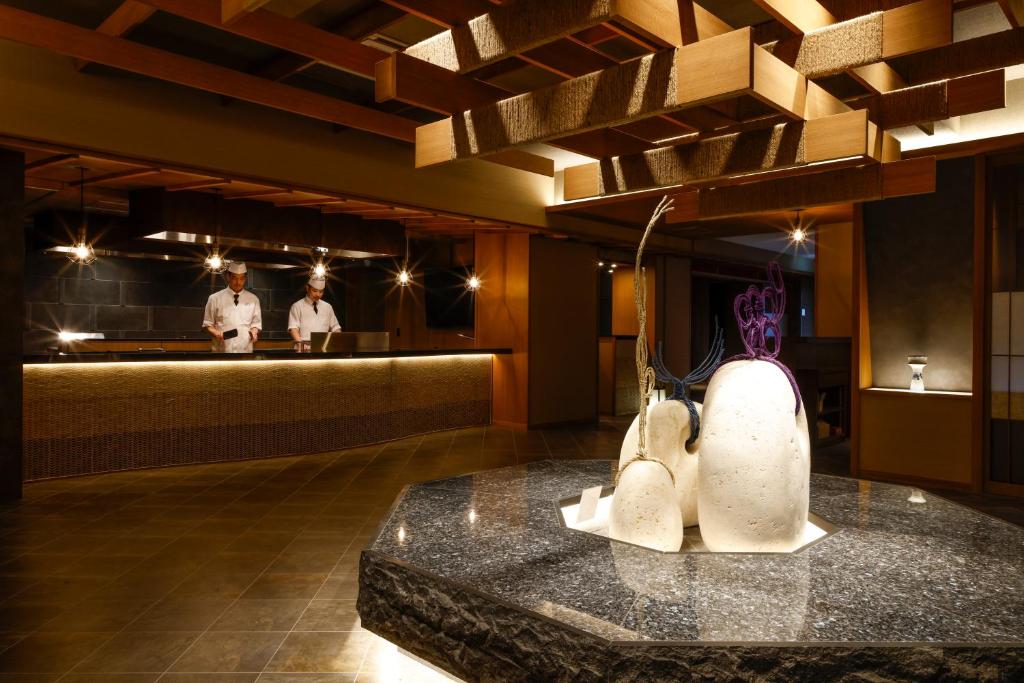 un restaurant avec un comptoir avec deux chefs en arrière-plan dans l'établissement Sun Urashima Yuki no Sato, à Toba 139 autres photos