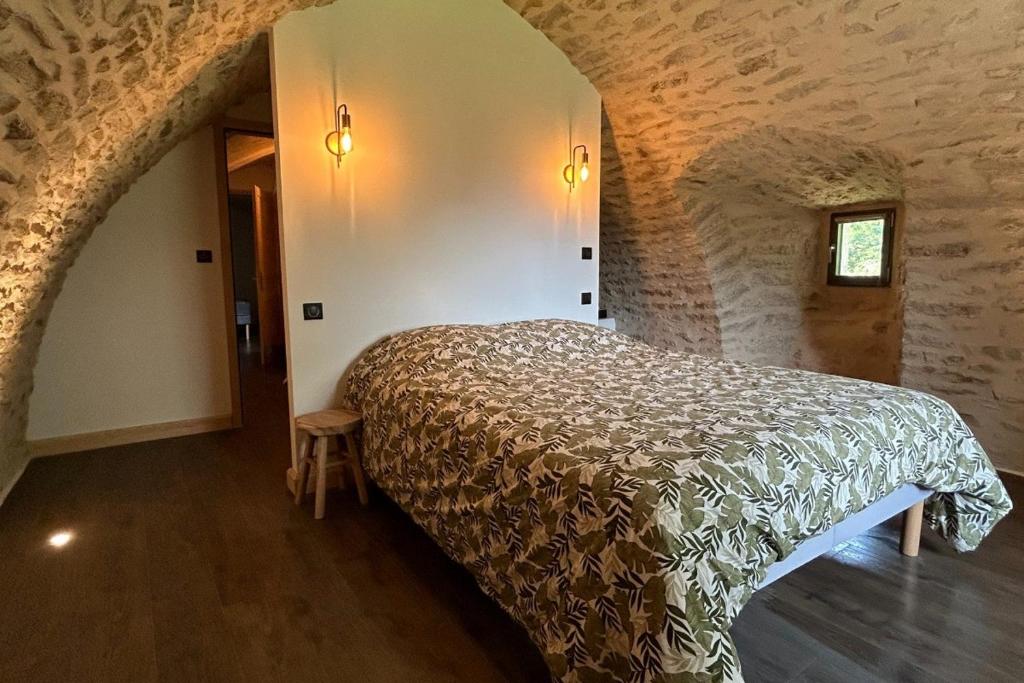 une chambre avec un lit dans un mur de pierre dans l'établissement Banassac Canilhac Gite pour 4 personnes avec piscine partagée et vue panoramique en Lozère, à Banassac