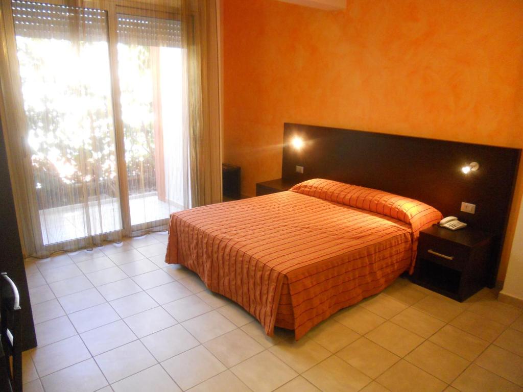 une chambre avec un lit et une grande fenêtre dans l'établissement Hotel Club Ravezzo, à Lido Marini