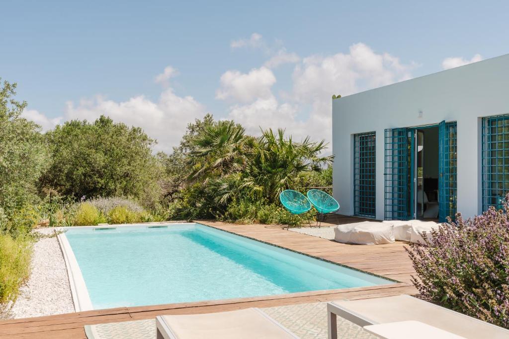 une piscine avec deux chaises à côté d'une maison dans l'établissement casa zabbara, à Balestrate